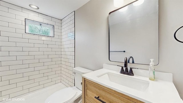 bathroom with toilet, vanity, and tiled shower