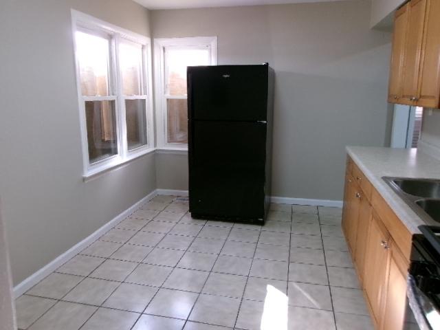 kitchen featuring light tile patterned floors, baseboards, freestanding refrigerator, light countertops, and stove