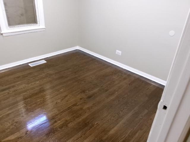 unfurnished room with visible vents, baseboards, and dark wood-style flooring