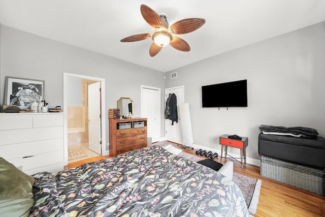 bedroom featuring wood finished floors, visible vents, baseboards, a closet, and connected bathroom