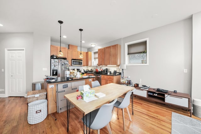 kitchen featuring dark countertops, light wood finished floors, recessed lighting, hanging light fixtures, and stainless steel appliances