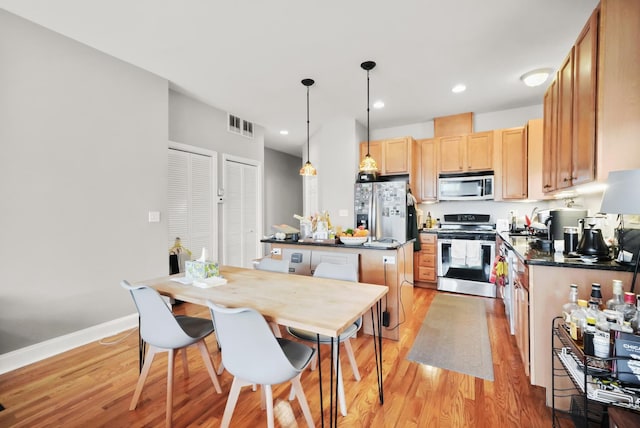 kitchen featuring visible vents, light wood finished floors, a kitchen island, appliances with stainless steel finishes, and dark countertops