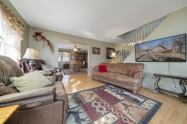 living room with ceiling fan, wood finished floors, and stairs