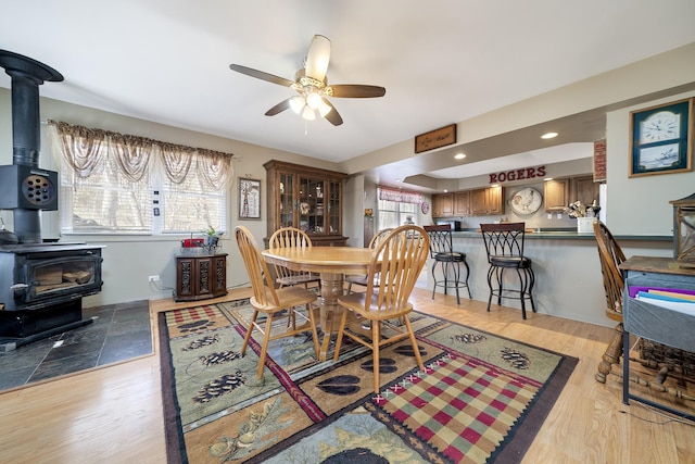 dining room with recessed lighting, light wood-style flooring, a wood stove, and a ceiling fan