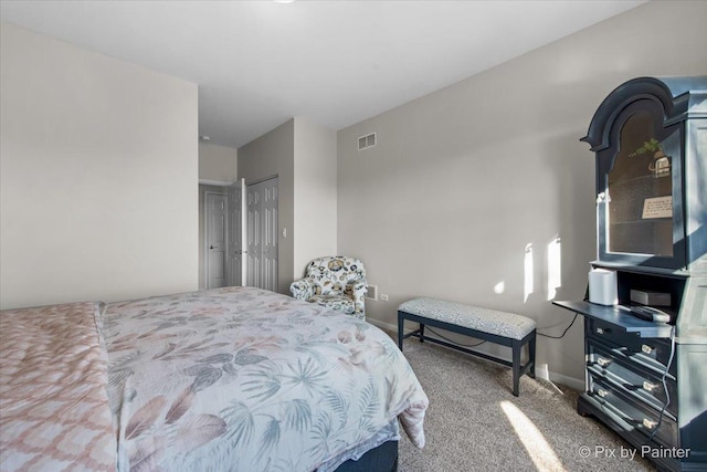 carpeted bedroom with visible vents, baseboards, and a closet