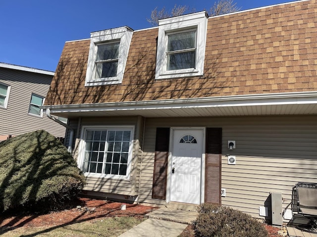 view of front of property with mansard roof and roof with shingles