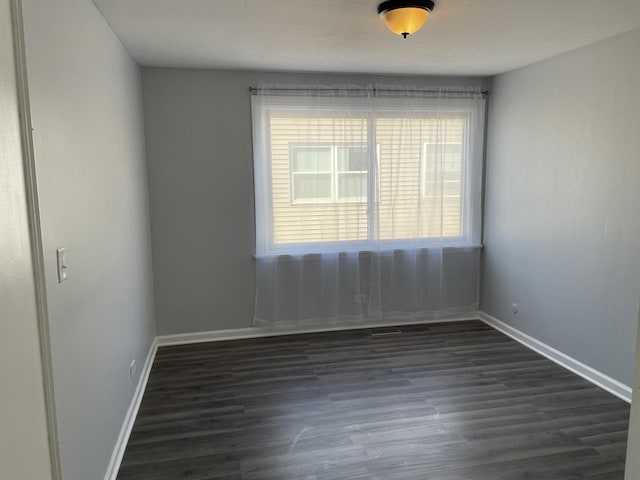 unfurnished room featuring baseboards and dark wood-style flooring