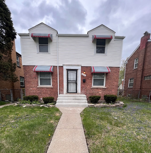 view of front of home with brick siding, a front lawn, and fence