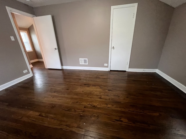 interior space with dark wood-type flooring, baseboards, and visible vents