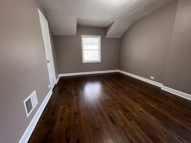 additional living space featuring visible vents, dark wood-type flooring, and baseboards