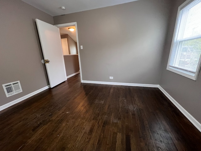 spare room featuring dark wood-type flooring, baseboards, and visible vents