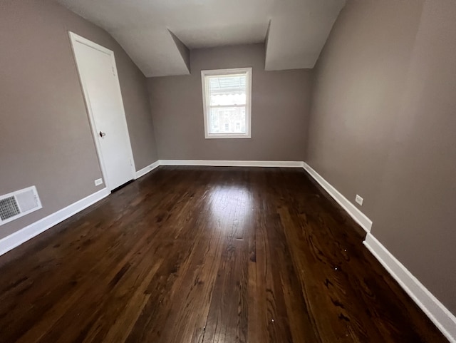 additional living space with visible vents, baseboards, dark wood-type flooring, and lofted ceiling