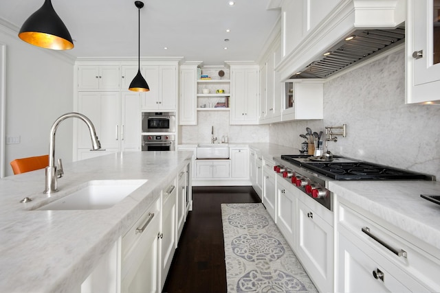 kitchen featuring white cabinets, premium range hood, appliances with stainless steel finishes, and a sink