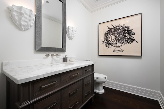 bathroom featuring vanity, wood finished floors, baseboards, crown molding, and toilet