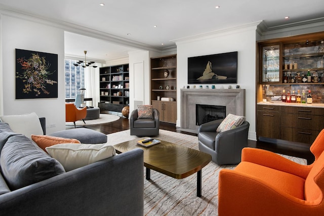 living room with ornamental molding, wood finished floors, a high end fireplace, recessed lighting, and a bar