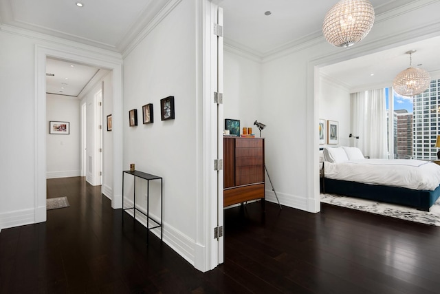 hall featuring dark wood finished floors, a notable chandelier, crown molding, and baseboards