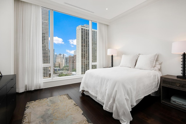 bedroom with wood-type flooring, a city view, and crown molding