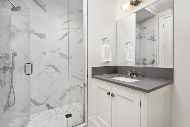 full bath featuring a marble finish shower and vanity