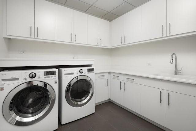 washroom with a sink, cabinet space, dark tile patterned floors, and washer and dryer