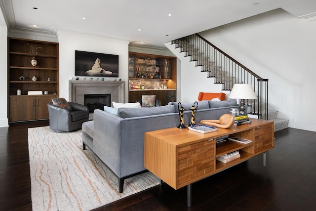 living room featuring hardwood / wood-style flooring, recessed lighting, stairway, crown molding, and a fireplace