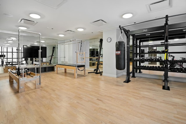 workout area featuring visible vents, crown molding, and wood finished floors