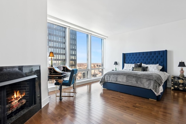 bedroom with expansive windows, a high end fireplace, and dark wood-style flooring