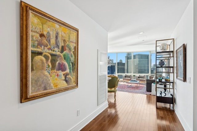 corridor featuring a view of city, dark wood-style floors, and baseboards