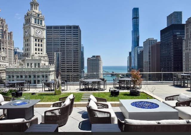 view of patio / terrace with a city view, a water view, and an outdoor living space with a fire pit