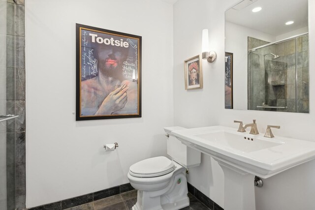 bathroom featuring toilet, recessed lighting, baseboards, and tiled shower