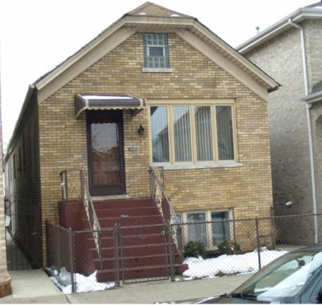 view of front of home with a gate, brick siding, and a fenced front yard