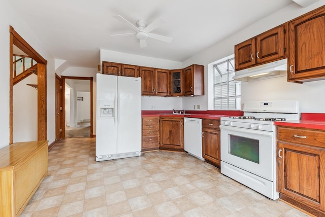 kitchen featuring white appliances, brown cabinetry, a ceiling fan, a sink, and under cabinet range hood