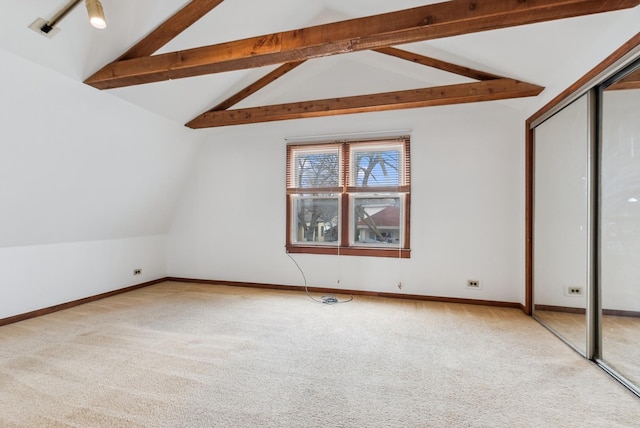 unfurnished bedroom with a closet, lofted ceiling with beams, baseboards, and carpet floors