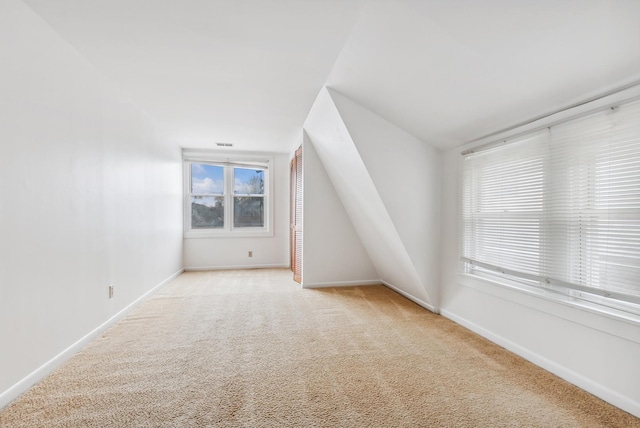 additional living space featuring visible vents, baseboards, and light carpet