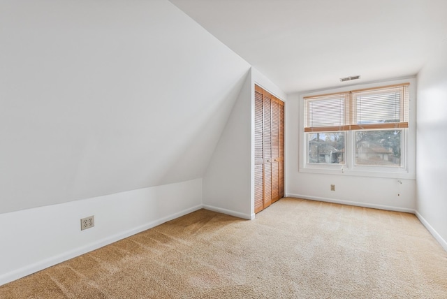 additional living space with visible vents, baseboards, carpet flooring, and vaulted ceiling