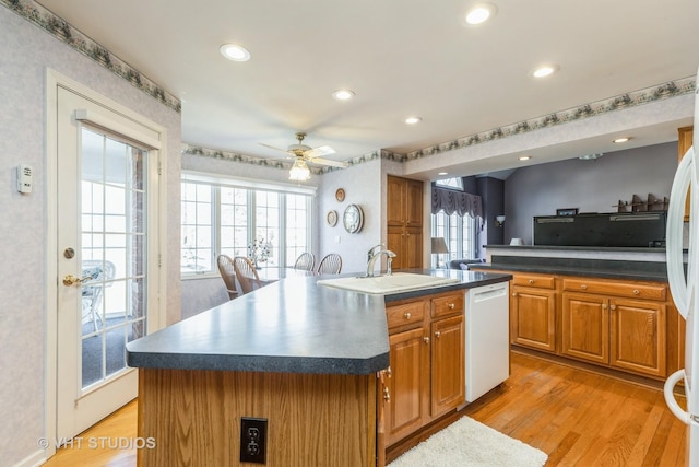 kitchen with a sink, dark countertops, dishwasher, and a ceiling fan