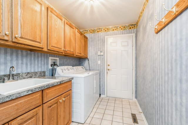 clothes washing area with wallpapered walls, light tile patterned flooring, cabinet space, independent washer and dryer, and a sink