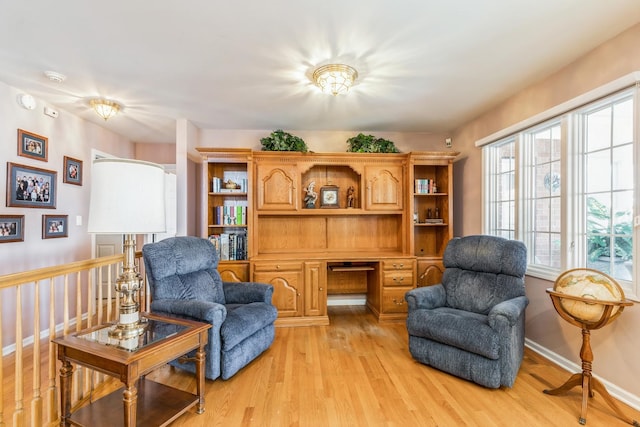 sitting room featuring light wood finished floors, built in study area, and baseboards