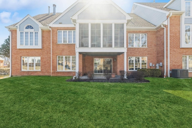 rear view of house with brick siding, a lawn, and cooling unit