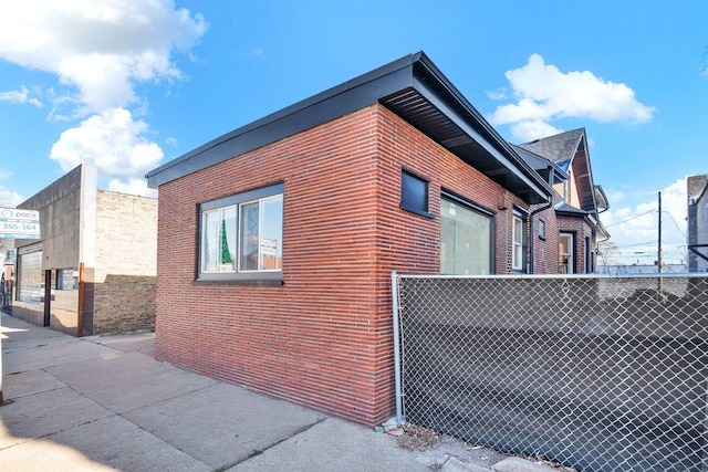 view of side of home featuring fence and brick siding