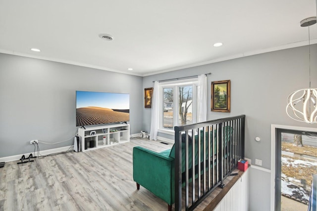 sitting room with wood finished floors, visible vents, baseboards, and ornamental molding