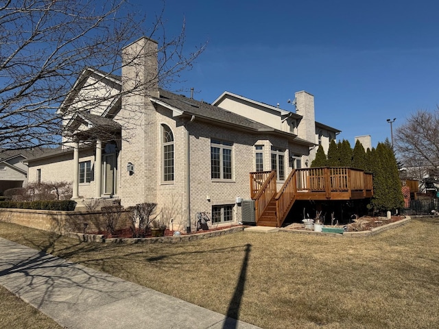 view of property exterior with a deck, a yard, brick siding, central AC unit, and a chimney