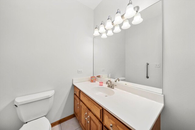 half bathroom featuring baseboards, toilet, vanity, and tile patterned flooring