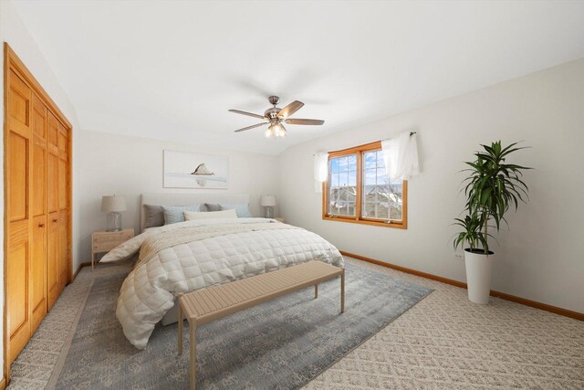 bedroom with a closet, baseboards, light colored carpet, and a ceiling fan