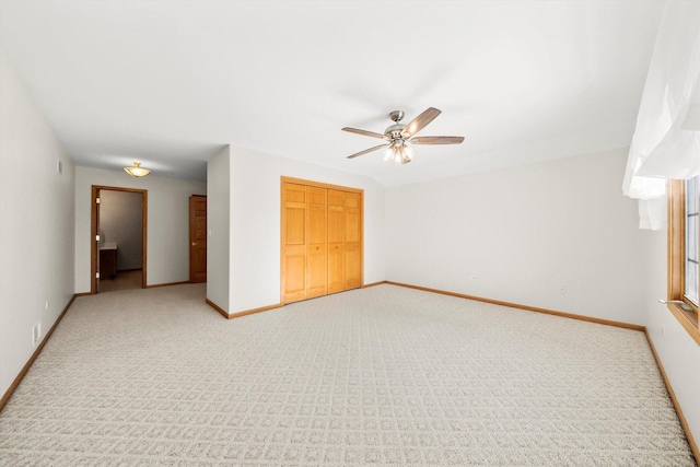 unfurnished bedroom with a closet, baseboards, light carpet, and ceiling fan