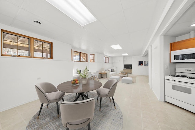 dining space featuring light tile patterned floors, visible vents, baseboards, and a drop ceiling