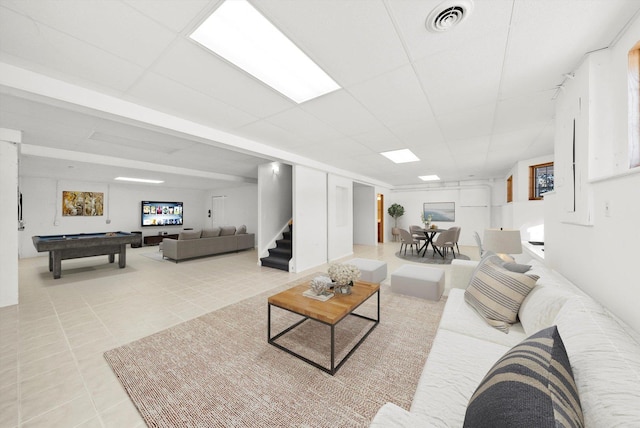 living room featuring light tile patterned floors, visible vents, stairs, pool table, and a paneled ceiling