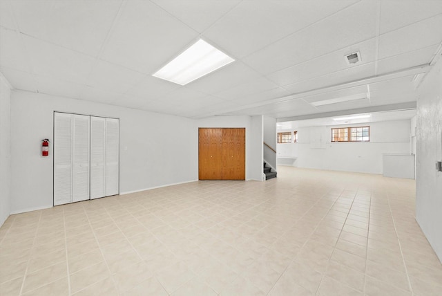 basement featuring stairway, a paneled ceiling, and visible vents