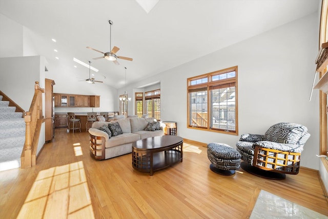 living area featuring high vaulted ceiling, light wood-style flooring, baseboards, a chandelier, and stairs