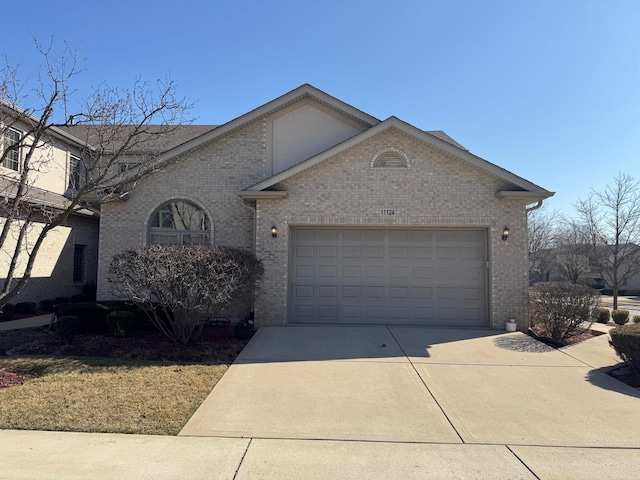 view of front of house with an attached garage, brick siding, and driveway