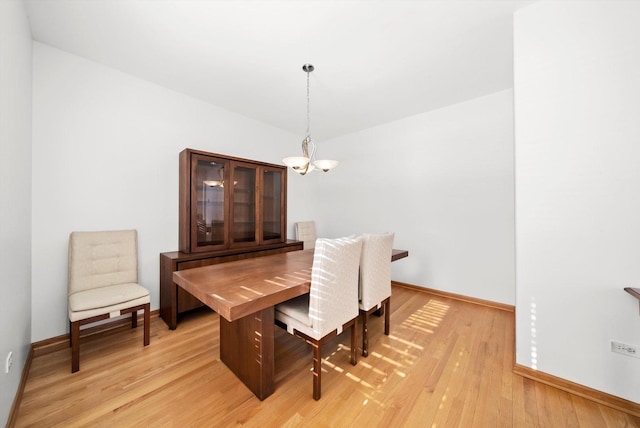 dining area with baseboards, an inviting chandelier, and light wood finished floors